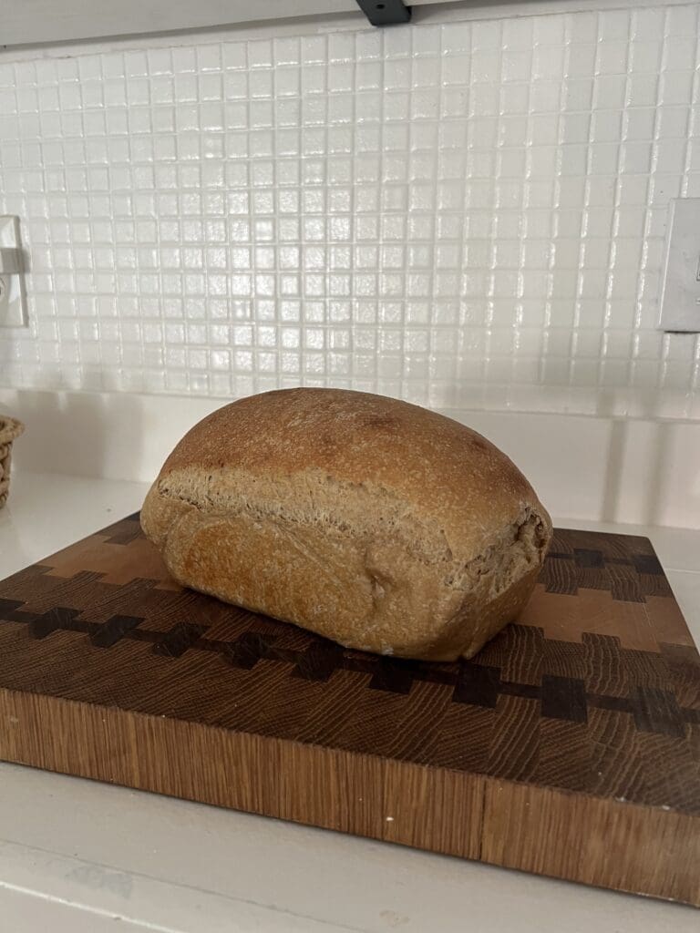 Sandwich loaf sitting on a wooden cutting board.